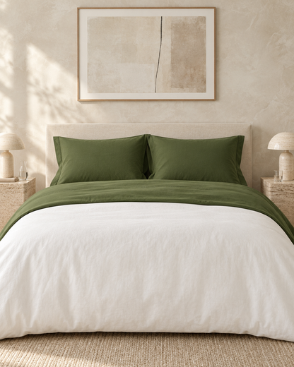 Olive Plain Cotton flat sheet turned down over a white duvet on a bed against a limewashed plaster wall