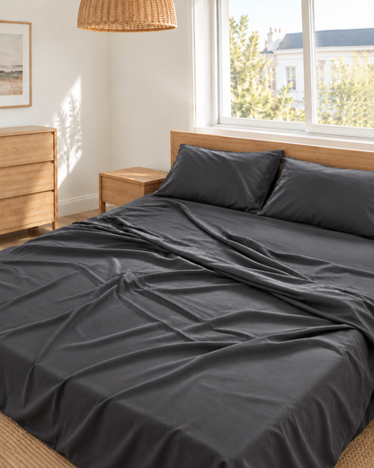 Charcoal Grey silky cotton flat sheet in grey 300 TC sateen on an oak bed in a bright bedroom.