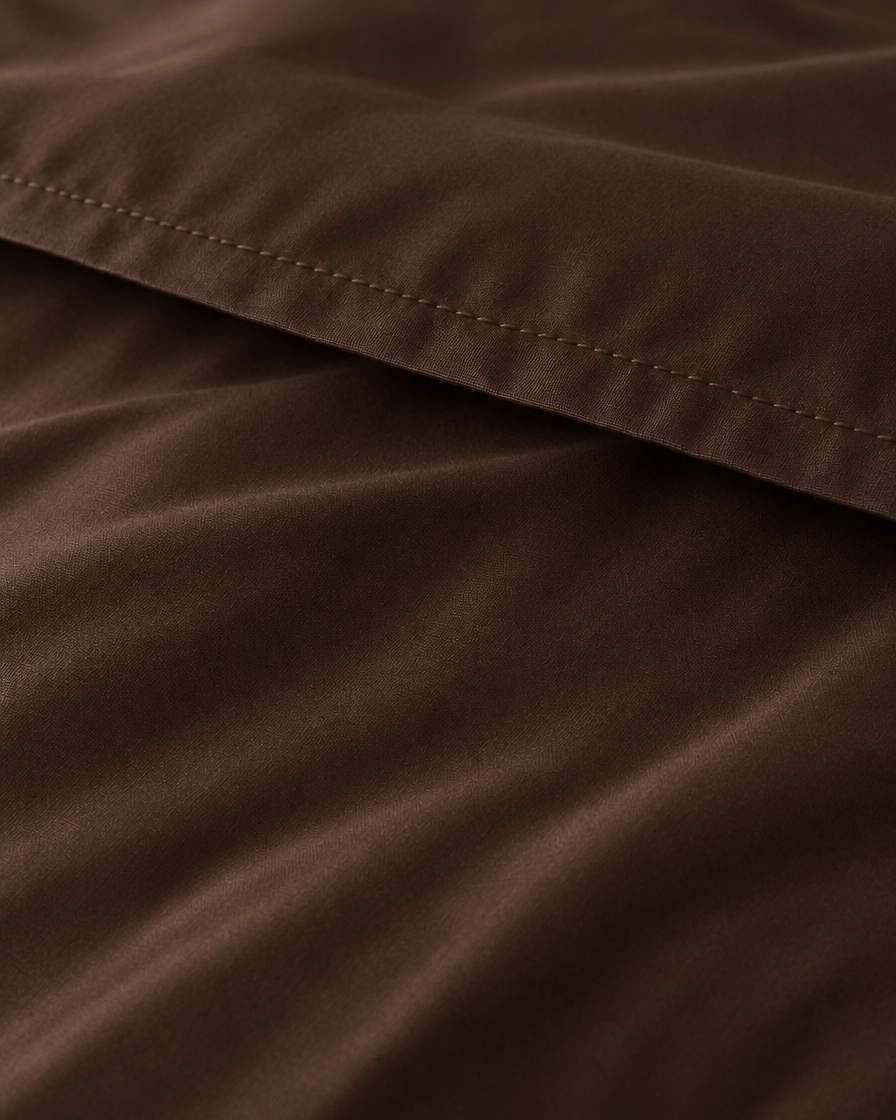 Macro of the stitched hem on a Chocolate silky cotton flat sheet, showing the chocolate brown sateen sheen.