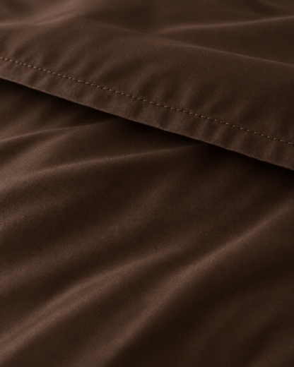 Macro of the stitched hem on a Chocolate silky cotton flat sheet, showing the chocolate brown sateen sheen.