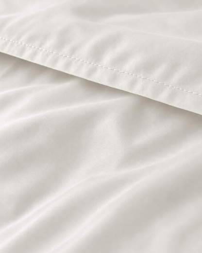 Macro of the stitched hem on a Milky White silky cotton flat sheet, showing the white sateen sheen.