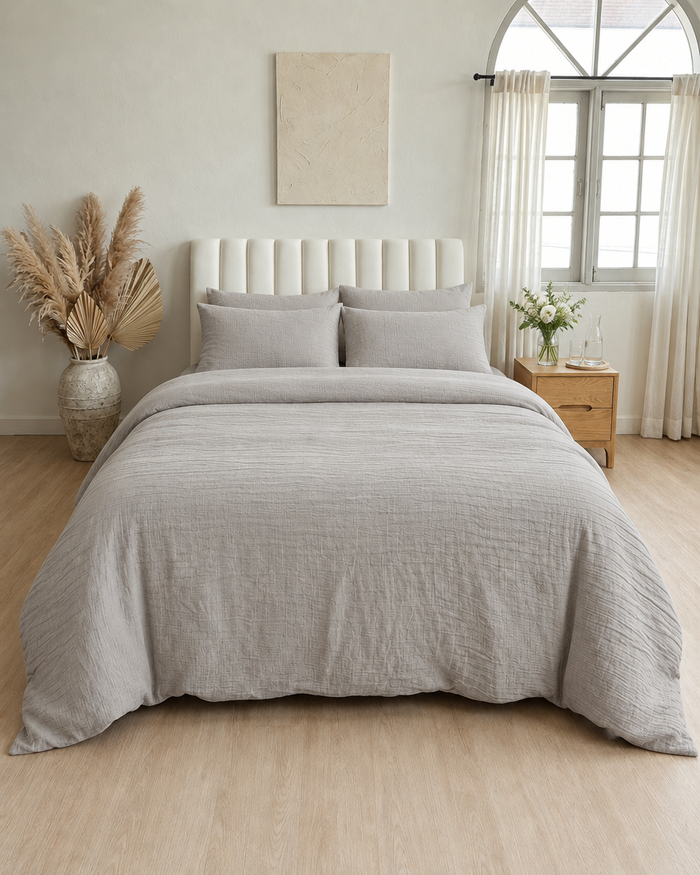 Freshly made guest bed in warm grey Cloud Cotton with folded towels