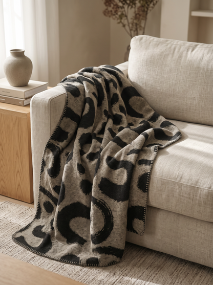 Ink Swirl Wool Blend Throw Blanket draped over a linen sofa