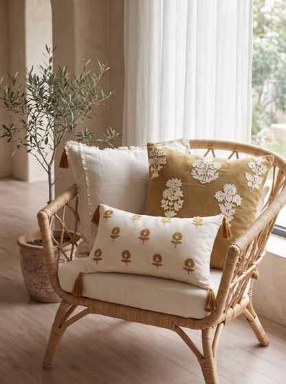 Mustard Floral Embroidery Cushion Covers on a rattan armchair by a window