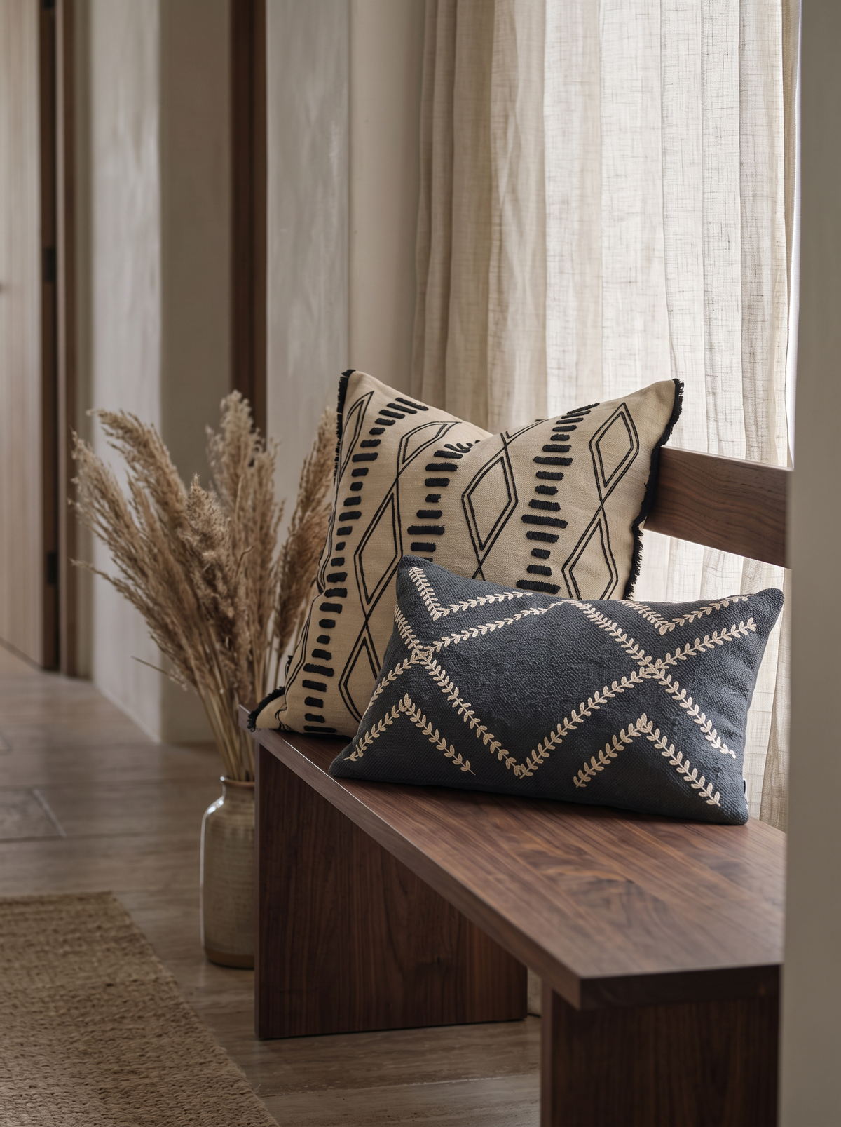 Sand & Black Ikat Embroidery Cushion Covers on a walnut bench