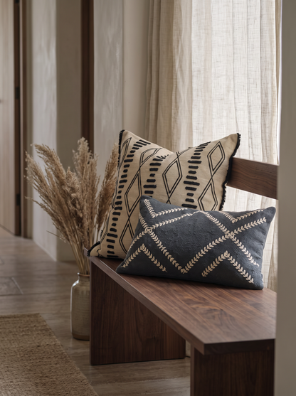 Sand & Black Ikat Embroidery Cushion Covers on a walnut bench
