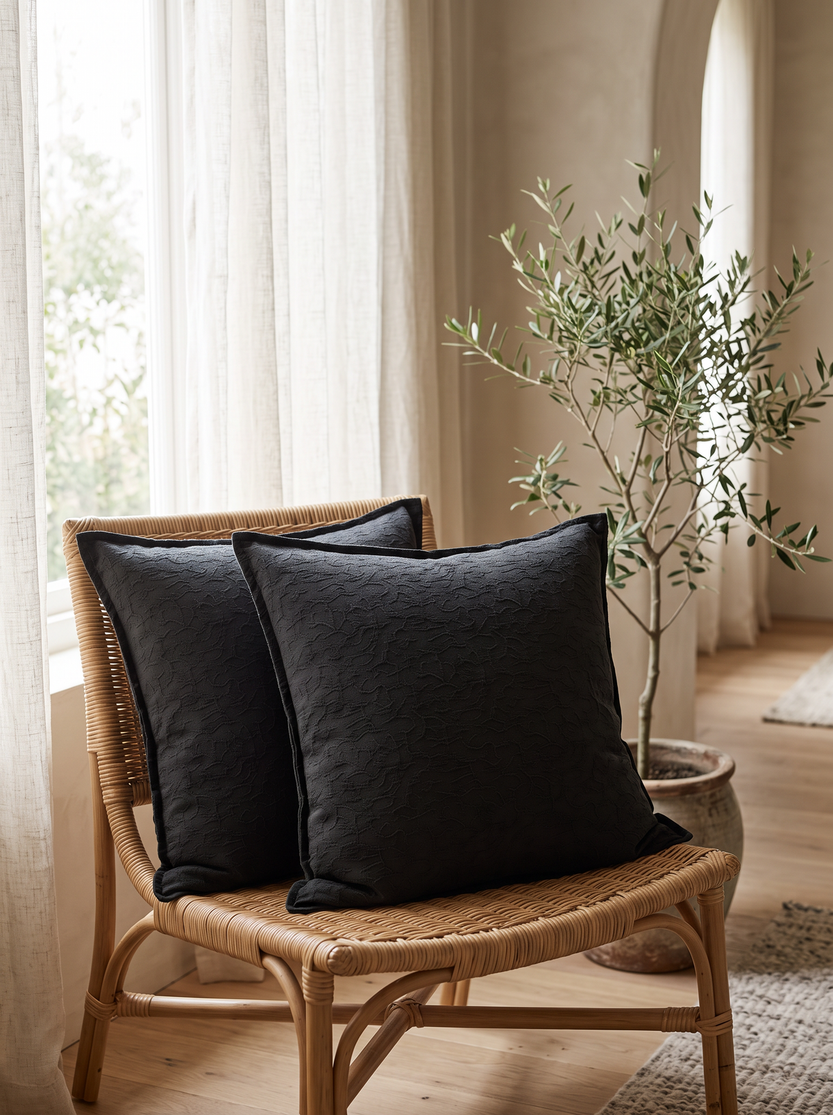 Charcoal Flanged Jacquard Cotton Linen Cushion Covers, styled at home on a rattan armchair by a window