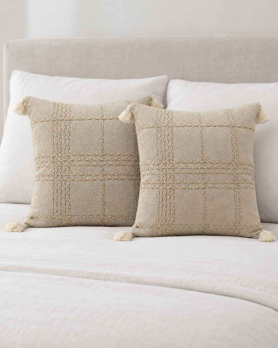 Two Oat Check Hand-Woven Linen Cotton cushion covers propped on a made bed