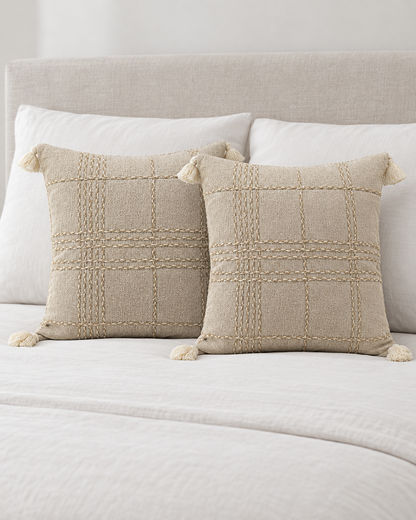 Two Oat Check Hand-Woven Linen Cotton cushion covers propped on a made bed