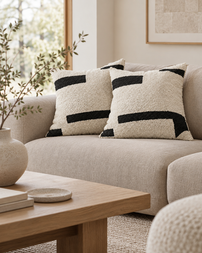 Ivory loop-pile cushions with black bar embroidery on a sofa in a Japandi lounge with a low oak table