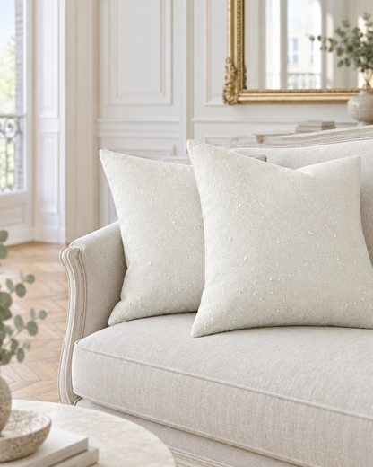 Ivory jacquard wool cushions on a pale settee in a Parisian salon with herringbone parquet