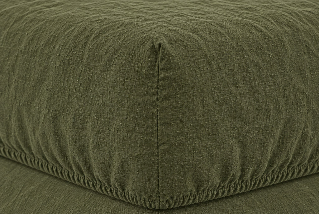 Macro of the elasticated corner and stitched seam of a Moss Green French linen fitted sheet on a mattress
