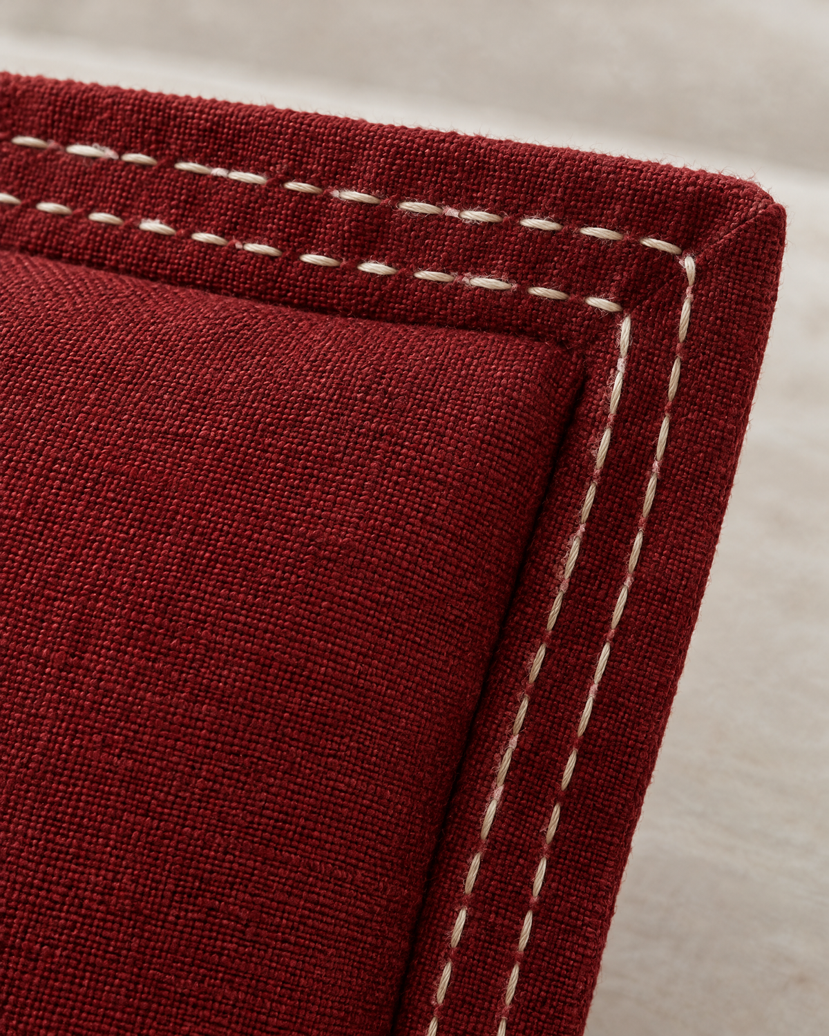 Macro close-up of the burgundy flange corner with two rows of ivory running stitch