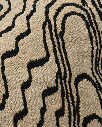 Macro close-up of black wood-grain embroidery with feathered stitch edges on a sand ground