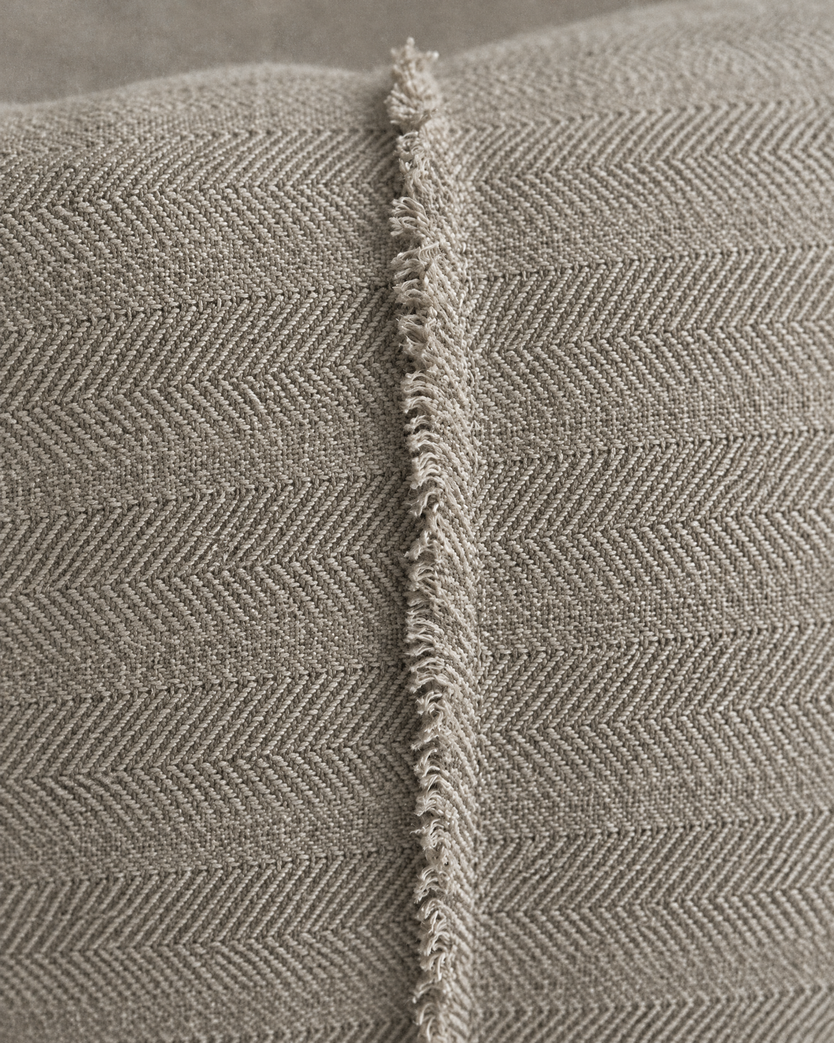 Macro close-up of the stone herringbone jacquard and its single frayed raised seam