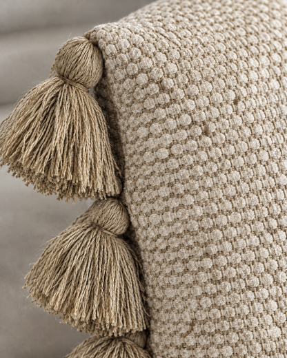 Macro close-up of the oat raised honeycomb weave with two chunky knotted khaki tassels along the side seam