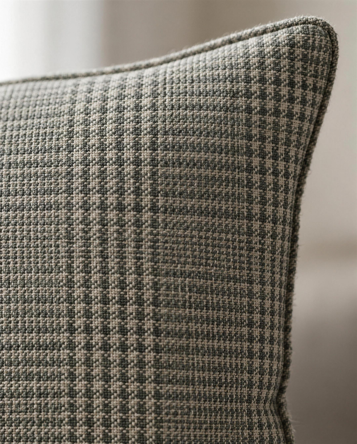 Macro close-up of the grey-green glen check jacquard with its fine dark self-piping at the corner