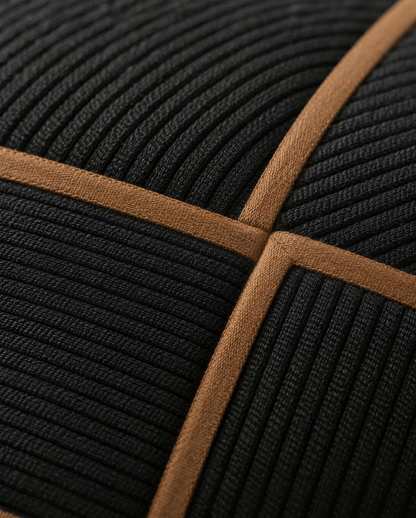 Macro close-up of black ribbed panels framed by narrow tan tape where two tapes meet on the basket weave lumbar