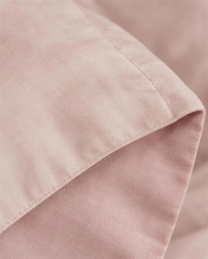 Macro close-up of the blush double-face cover folded at the flange to show its two pink faces and topstitched line