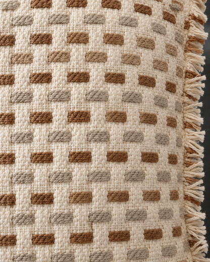 Macro close-up of rows of raised caramel, tan and greige dashes on a cream basket weave with a frayed self-fringe