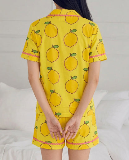 Person wearing a yellow pajama set with lemon pattern on a white background