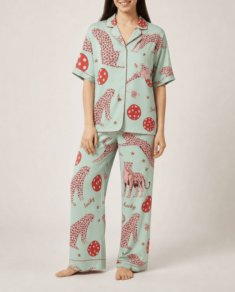 Person wearing a light blue pajama set with pink animal prints on a plain background
