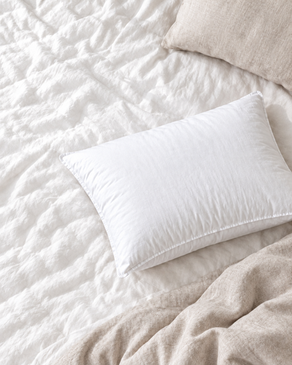 White Microgel Pillow Insert on a softly rumpled bed, seen from above beside a breakfast tray and open magazine