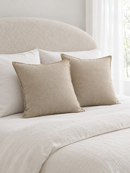Oat slub linen cotton cushions on ivory bedding under sheer white curtains