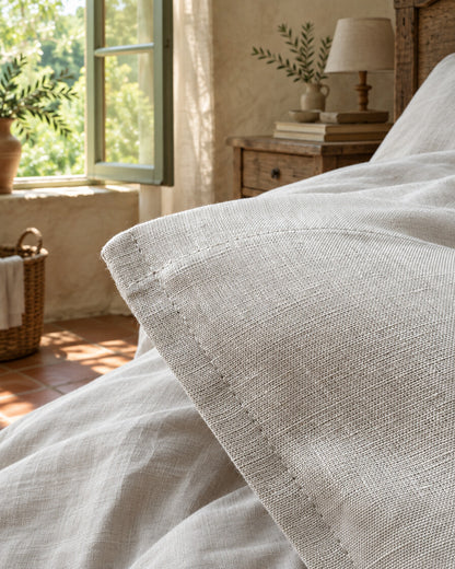 White French linen pillowcase and its hem, styled in a relaxed European country-house bedroom