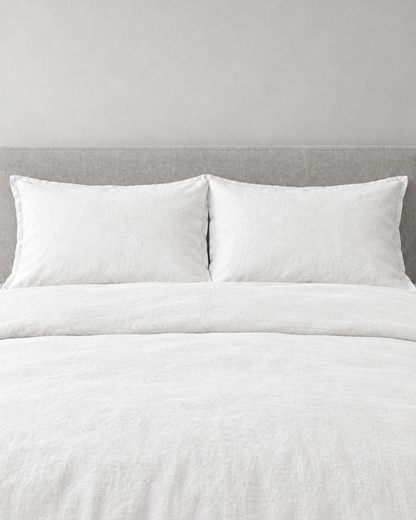 Snow white French linen pillowcases on a snow white linen bed, front view