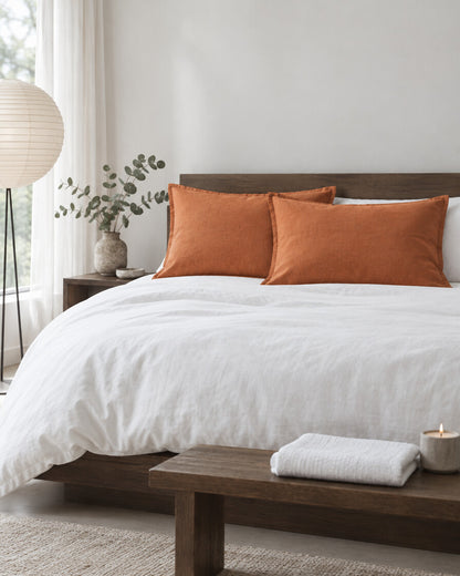 Terracotta French linen pillowcases in a calm Japandi bedroom on a low dark-oak bed