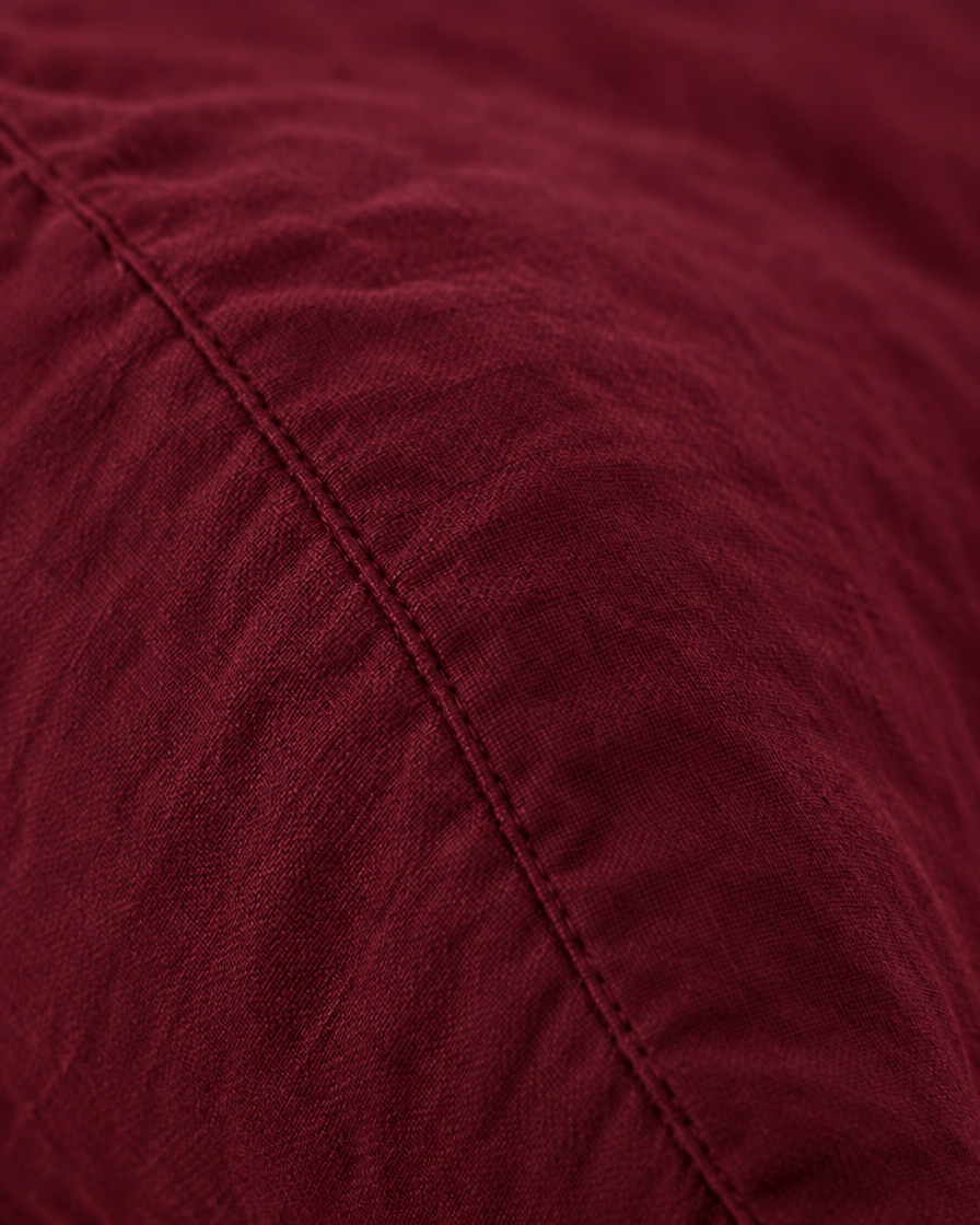 Macro of the stitched seam on a Burgundy Red pillow in plain cotton pillowcases.
