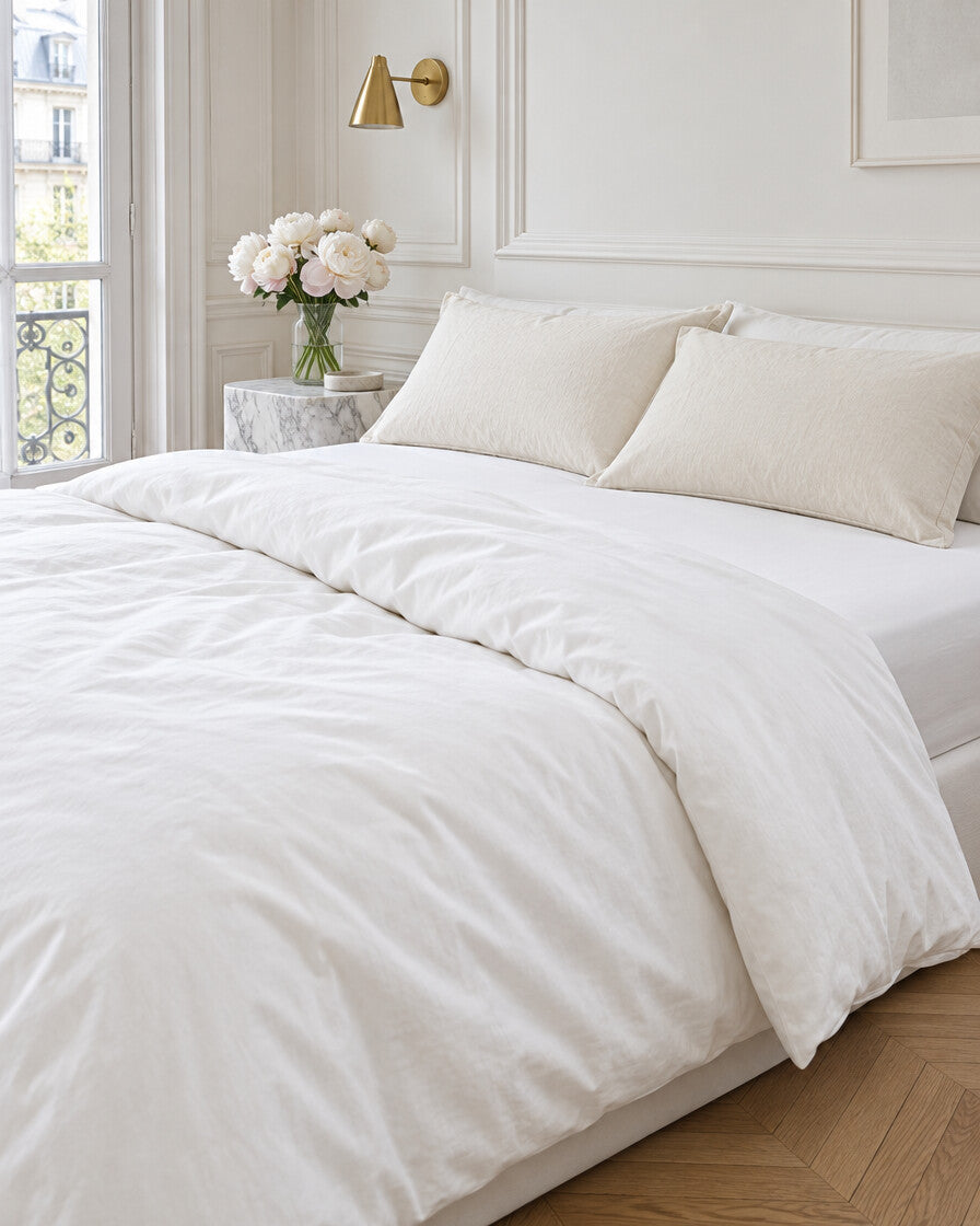 Ivory plain cotton pillowcases in a Parisian bedroom with panelled walls and fresh peonies