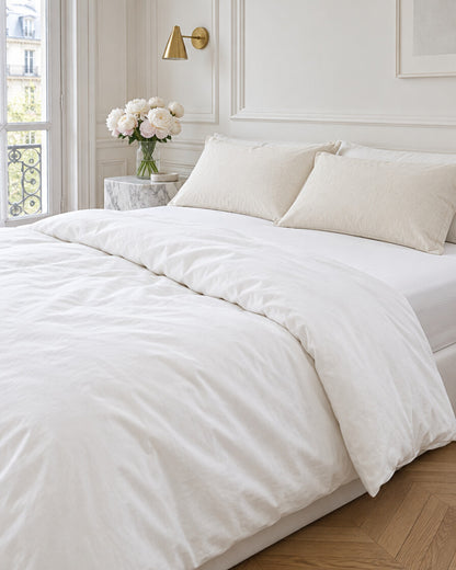 Ivory plain cotton pillowcases in a Parisian bedroom with panelled walls and fresh peonies