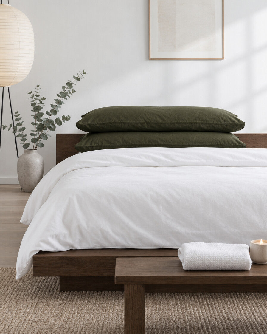 Olive green plain cotton pillowcases in a calm Japandi bedroom on a low dark-oak bed