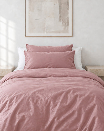 Rose Pink silky cotton pillowcases on pillows against a white bed between bedside lamps