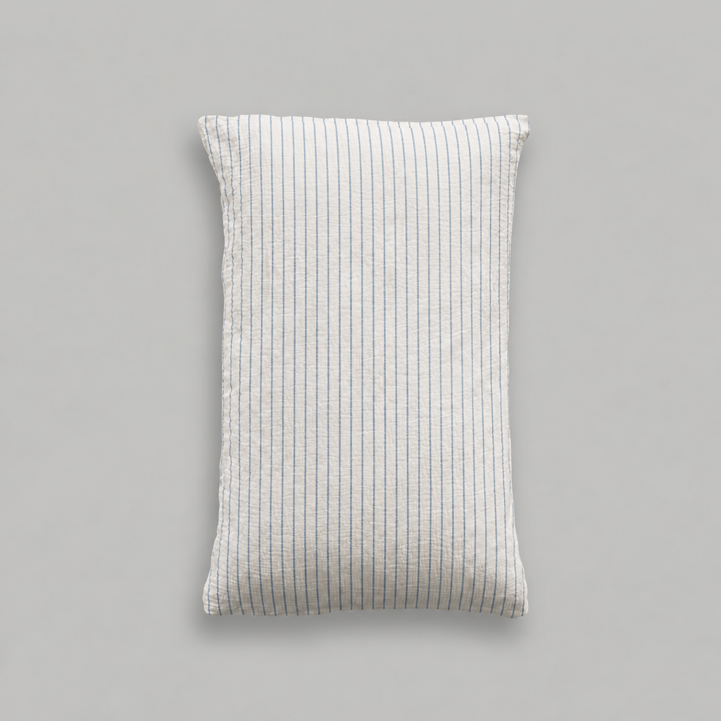 Single cloud cotton pillowcase with fine Blue Pinstripe on soft off-white crinkled muslin, studio shot.