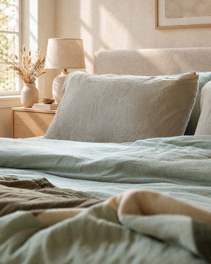 Grey-green cloud cotton pillows and bedding, styled in a calm sunlit Scandinavian bedroom
