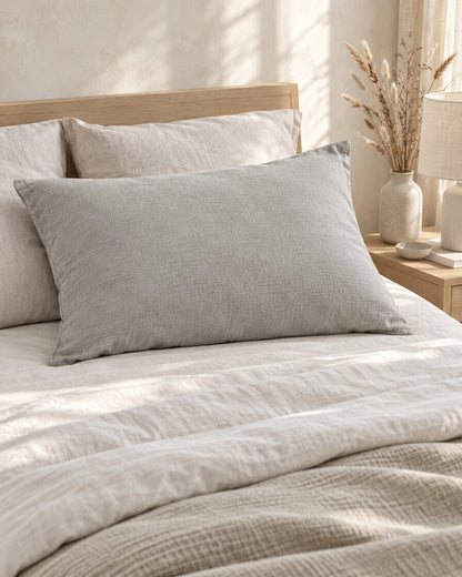 Warm Grey cloud cotton pillowcase, styled in a calm sunlit Scandinavian bedroom