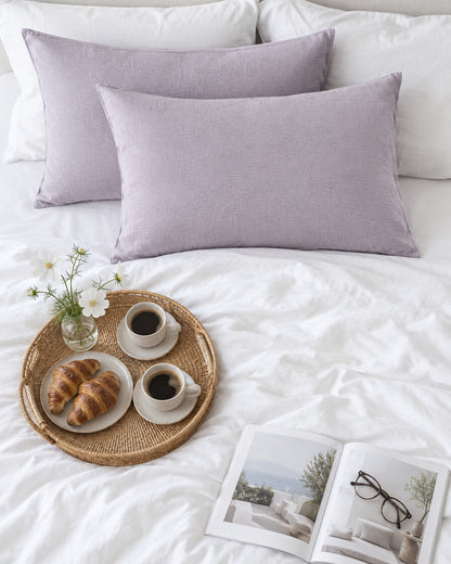 Taro lilac cloud cotton pillowcases seen from above with a breakfast tray of coffee and croissants