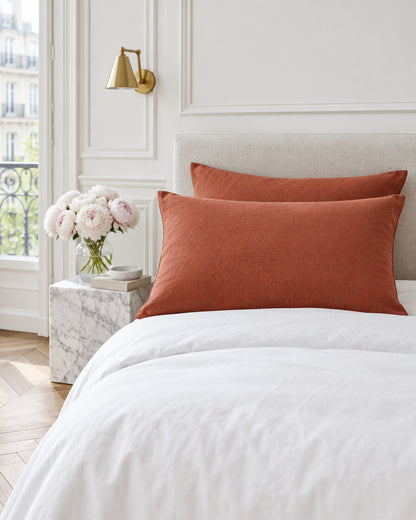 Copper cloud cotton pillowcases in a Parisian bedroom with panelled walls and fresh peonies