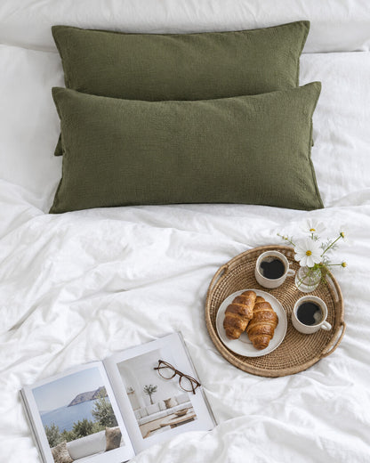 Juniper green cloud cotton pillowcases seen from above with a breakfast tray of coffee and croissants