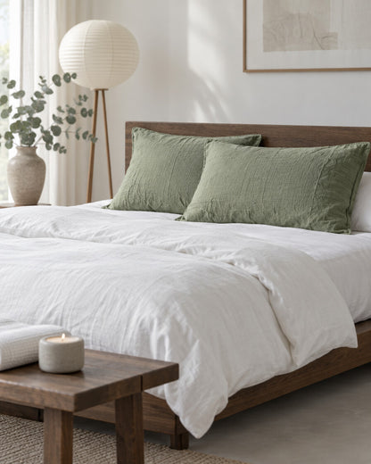 Sage green cloud cotton pillowcases in a calm Japandi bedroom on a low dark-oak bed