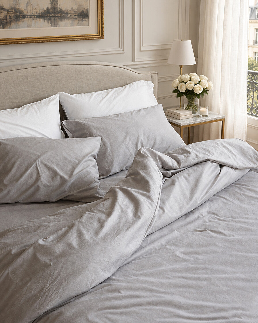 Pale grey silky cotton bedding, styled in an elegant Parisian apartment bedroom