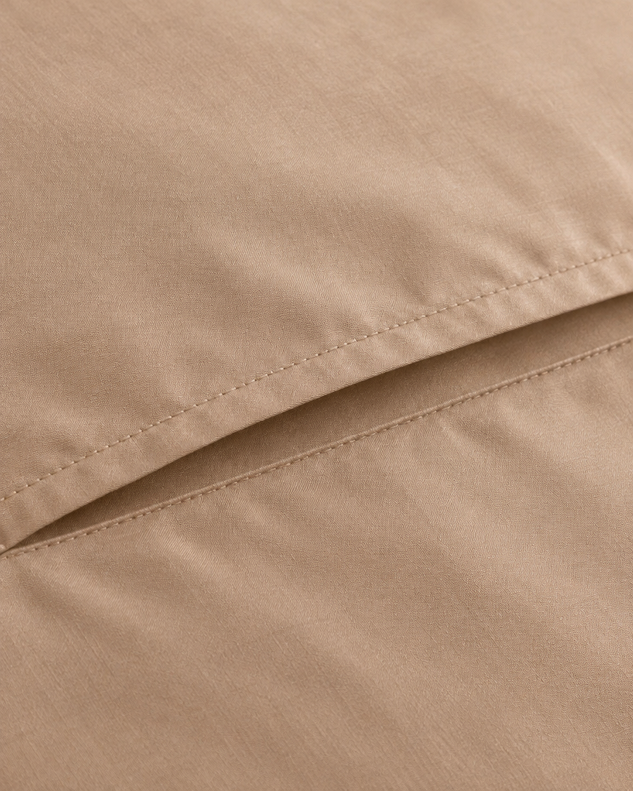 Close-up of the stitched envelope hem on a light beige silky cotton sateen pillowcase