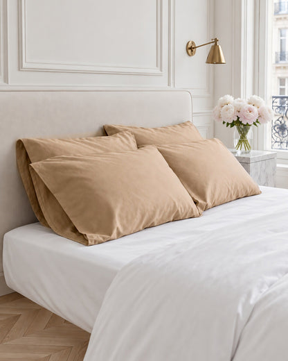 Light Beige silky cotton sateen pillowcases stacked on a white bed in a panelled Parisian bedroom