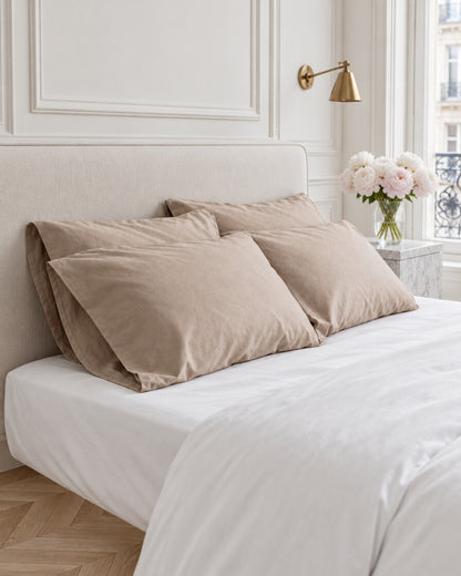 Taupe silky cotton pillowcases in a Parisian bedroom with panelled walls and fresh peonies