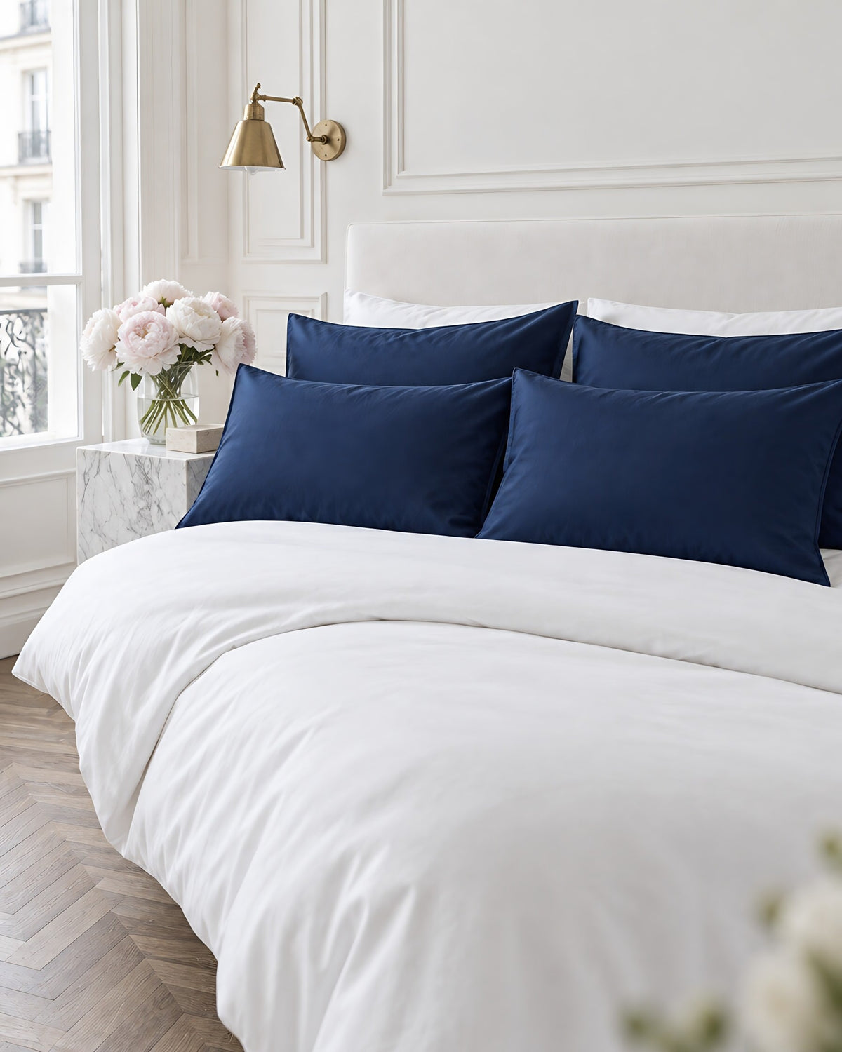 Marine Blue silky cotton pillowcases in a Parisian bedroom with panelled walls and fresh peonies