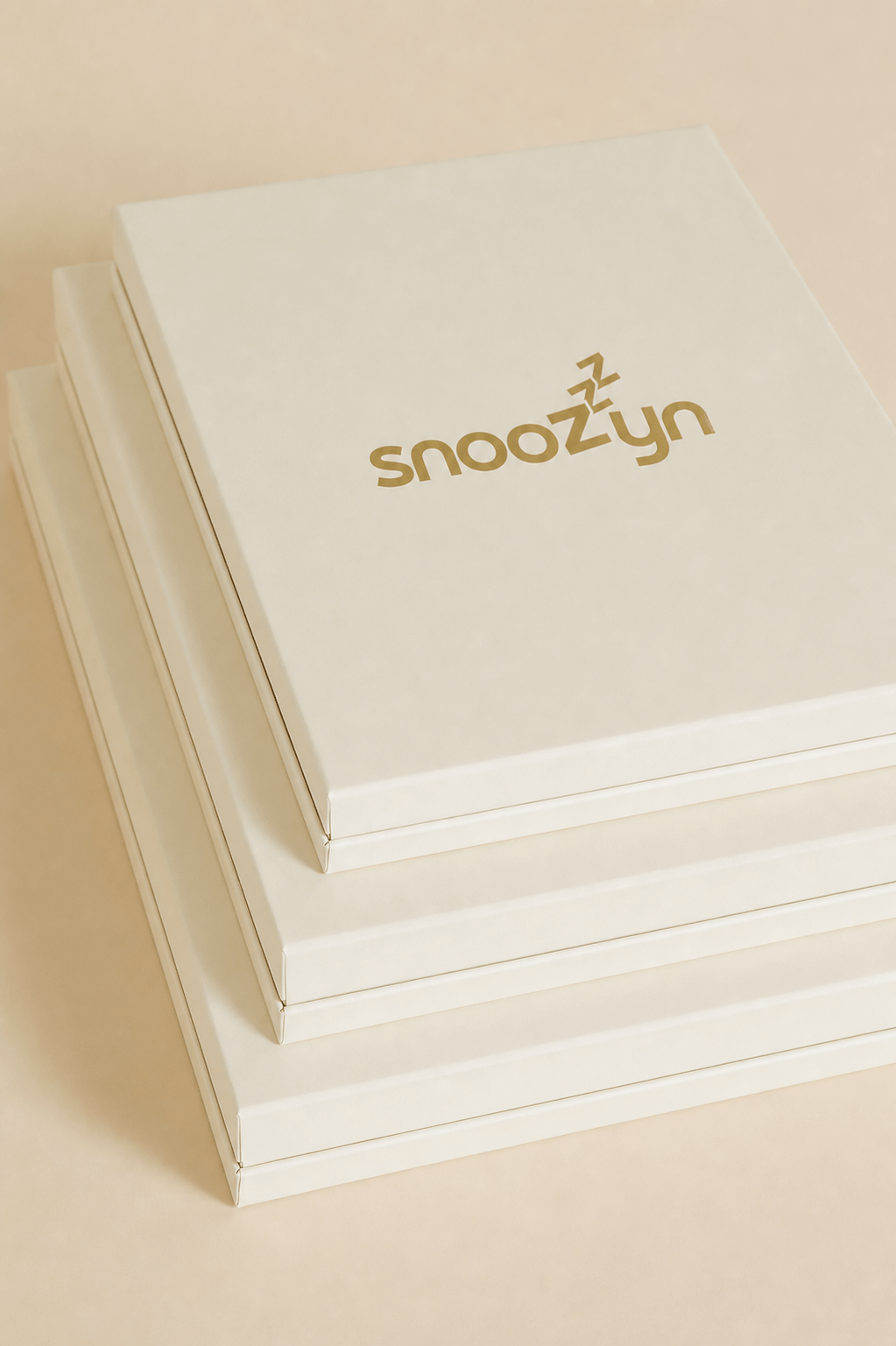 Stack of white boxes with 'snoozyn' branding on a beige background