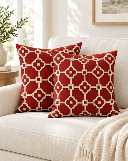 Two red and ivory lattice embroidered ramie cotton cushions on a cream linen sofa beside a knitted throw